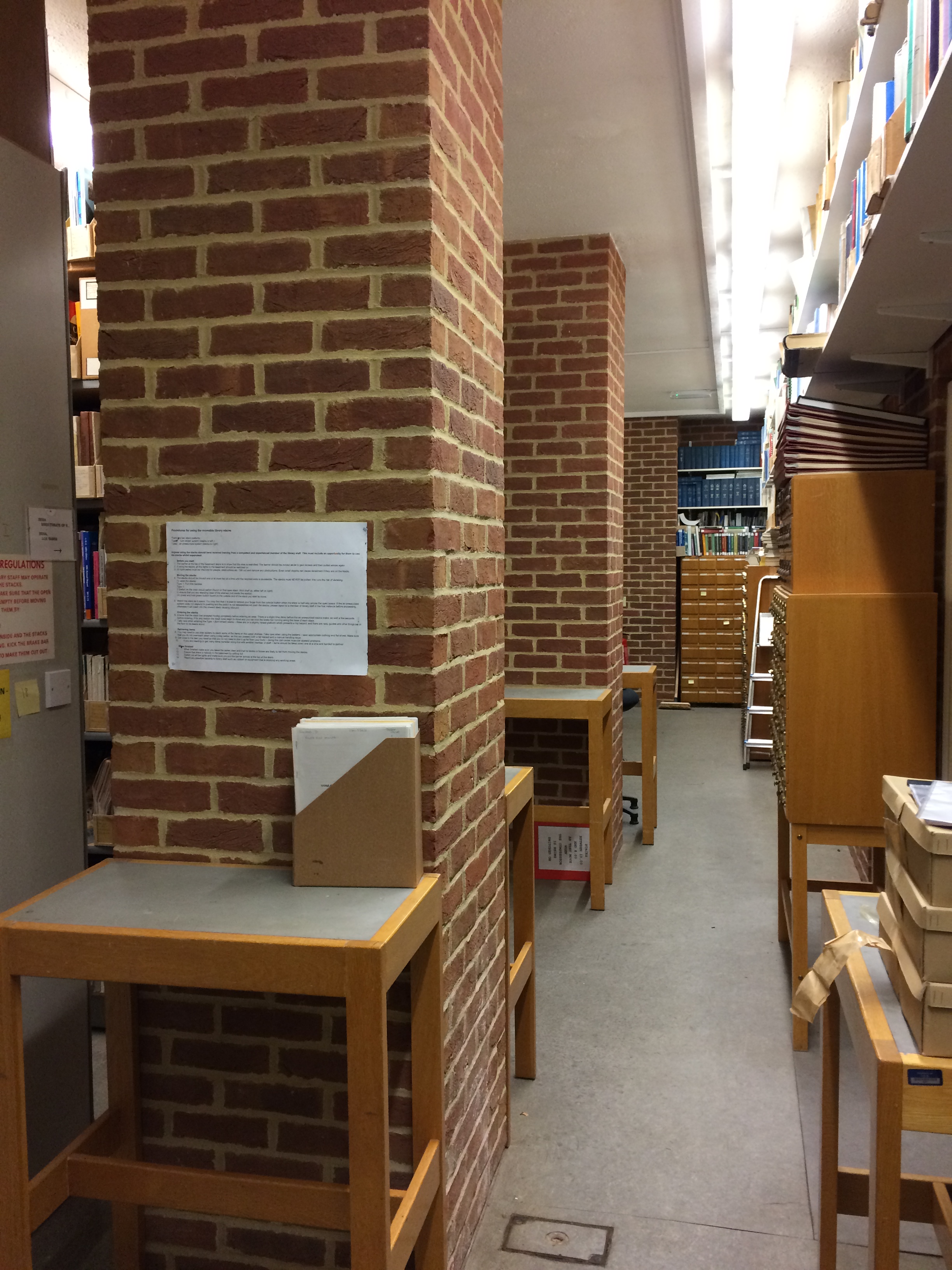 Two red brick pillars, 4 small tall tables, card catalogue units, MDF shelving on walls